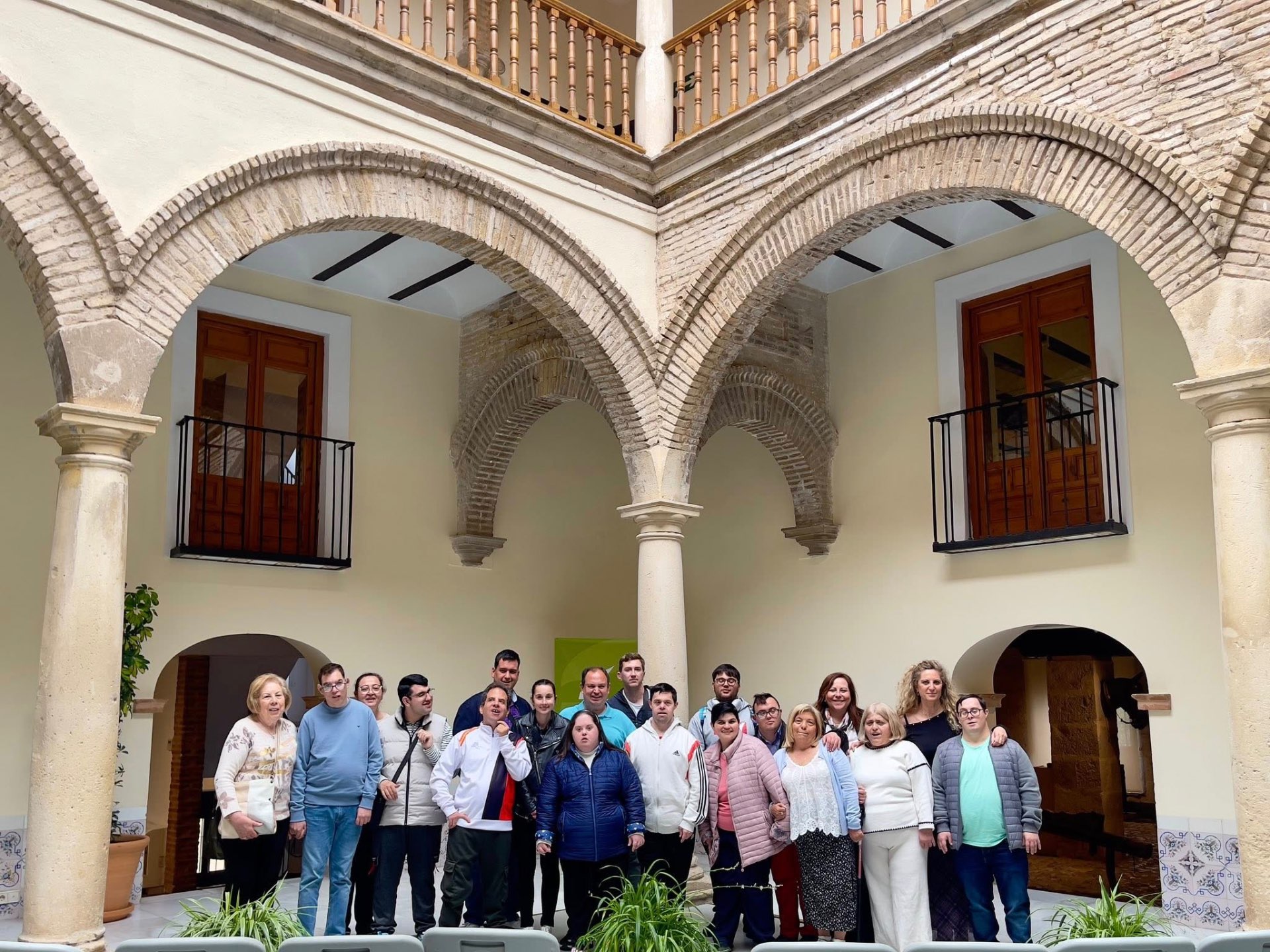Fotografía real del grupo del Programa posando bajo los arcos de ladrillo y las columnas de un patio andaluz tradicional durante una salida cultural.