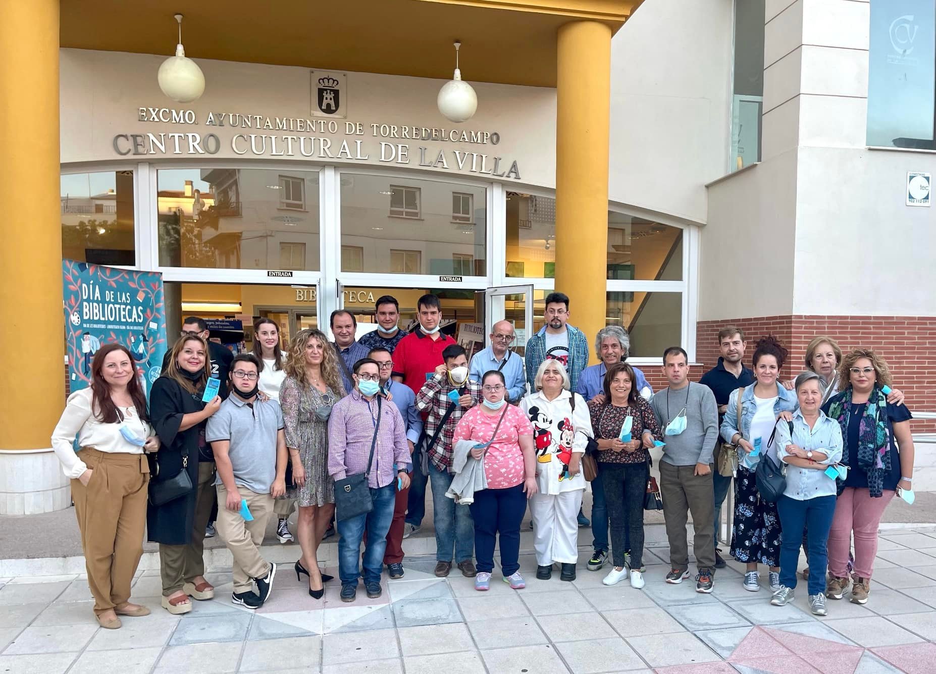 Fotografía real del grupo del Programa posando a la entrada del Centro Cultural de la Villa del Excmo. Ayuntamiento de Torredelcampo, junto al cartel del Día de las Bibliotecas.